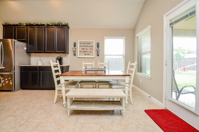 dining area featuring baseboards, light tile patterned floors, and lofted ceiling