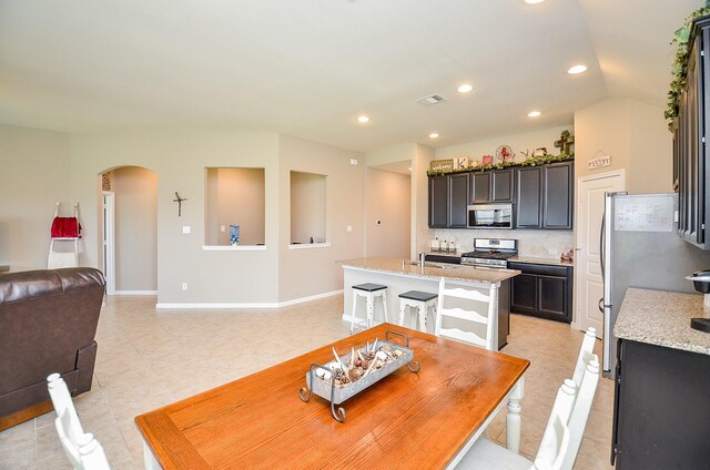 dining area with arched walkways, recessed lighting, baseboards, light tile patterned floors, and visible vents