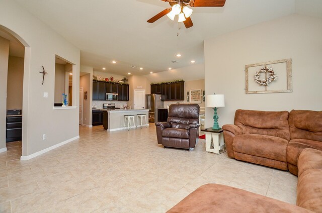 living room with light tile patterned flooring, baseboards, ceiling fan, recessed lighting, and arched walkways