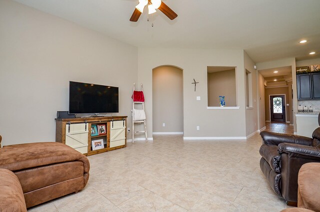 living room featuring ceiling fan, arched walkways, light tile patterned floors, baseboards, and recessed lighting