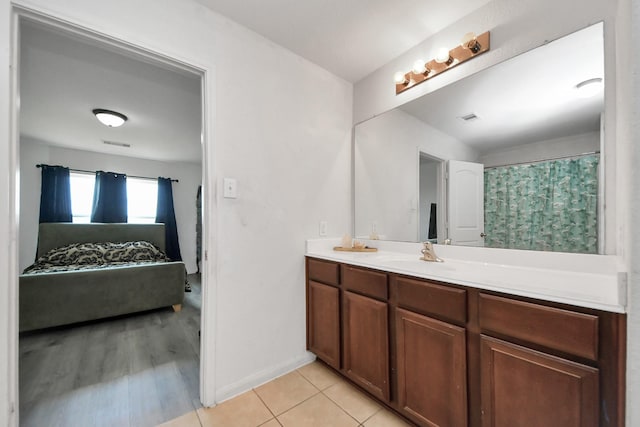 full bathroom featuring double vanity, visible vents, a sink, baseboards, and connected bathroom