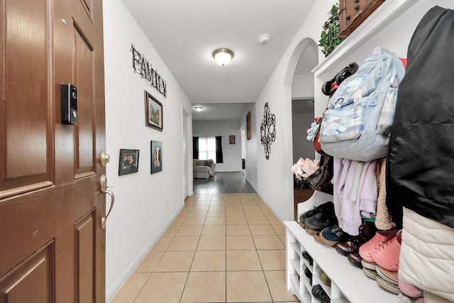 hall featuring baseboards and light tile patterned floors