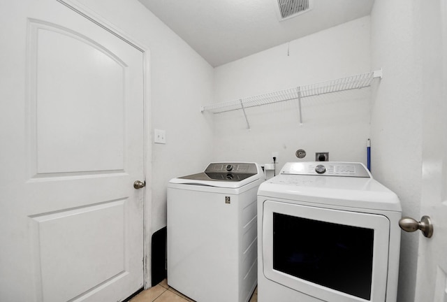 laundry area with laundry area, light tile patterned flooring, washer and dryer, and visible vents