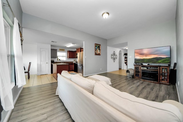 living room featuring arched walkways, baseboards, and light wood-type flooring