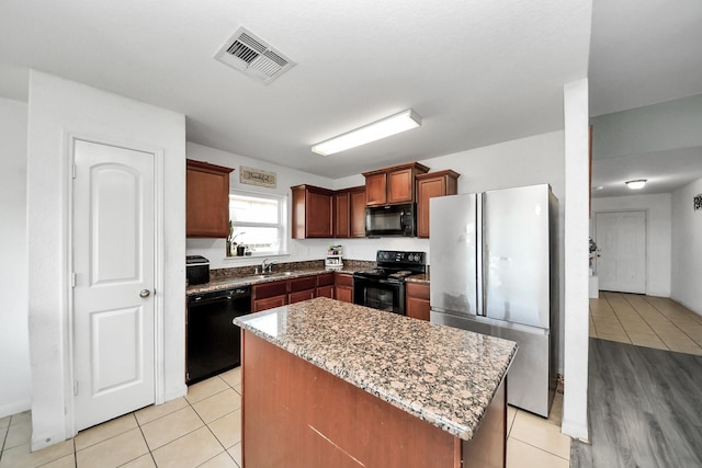 kitchen with a sink, light tile patterned floors, black appliances, and visible vents