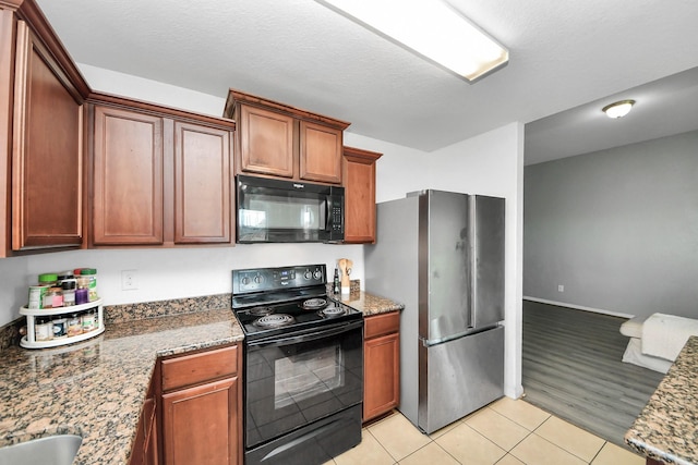 kitchen featuring light tile patterned floors, stone countertops, and black appliances
