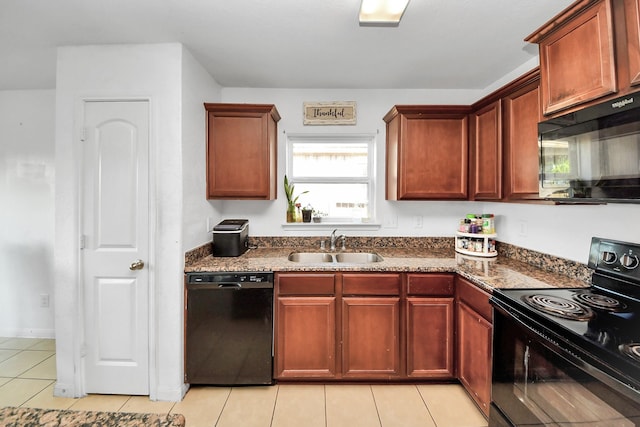 kitchen featuring a sink, dark stone counters, black appliances, and light tile patterned flooring