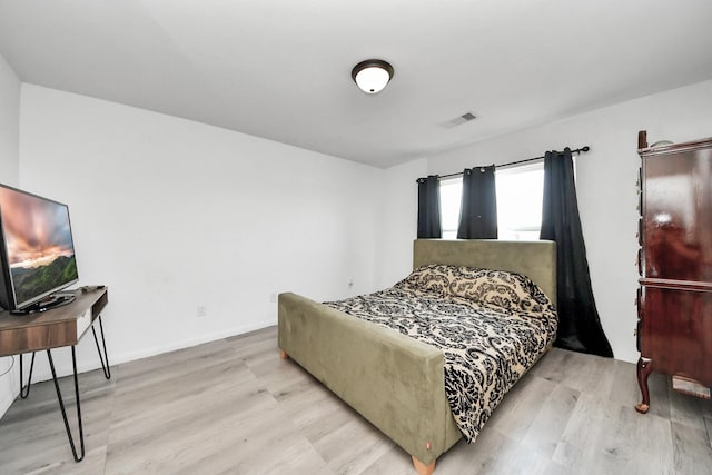 bedroom featuring baseboards, visible vents, and wood finished floors