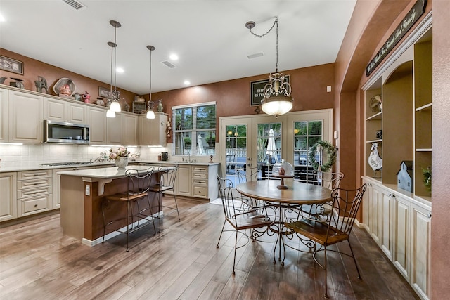 kitchen with a kitchen breakfast bar, a kitchen island, appliances with stainless steel finishes, tasteful backsplash, and wood finished floors