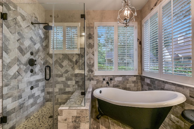 full bath featuring a freestanding bath, a shower stall, a chandelier, and a wealth of natural light