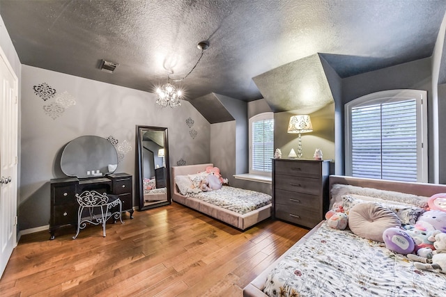 bedroom with a chandelier, hardwood / wood-style flooring, a textured ceiling, and visible vents