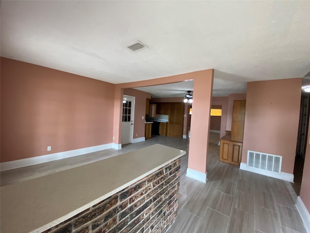 interior space with baseboards, visible vents, and ceiling fan