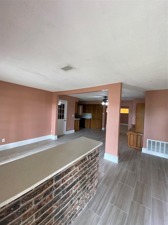 unfurnished living room with a textured ceiling, baseboards, and visible vents