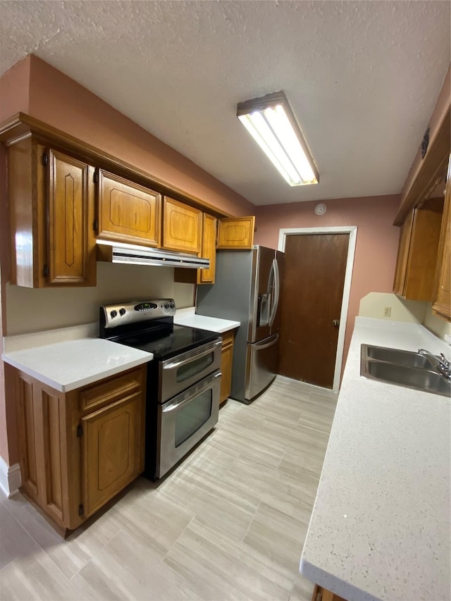 kitchen featuring a sink, appliances with stainless steel finishes, under cabinet range hood, and light countertops