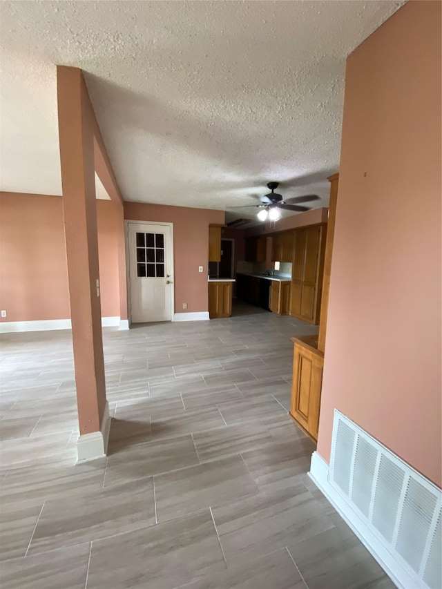 interior space featuring visible vents, wood tiled floor, a textured ceiling, and baseboards