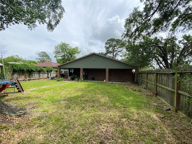 back of house featuring a fenced backyard, a yard, and brick siding