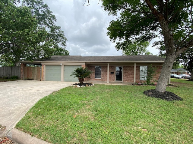 ranch-style home with fence, an attached garage, concrete driveway, and a front yard