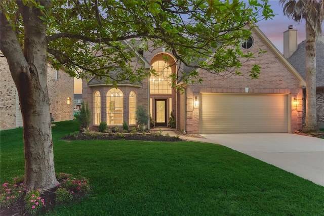 traditional home with a garage, a front yard, a chimney, brick siding, and driveway