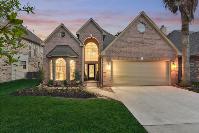 french country inspired facade featuring an attached garage, brick siding, a front yard, a chimney, and concrete driveway