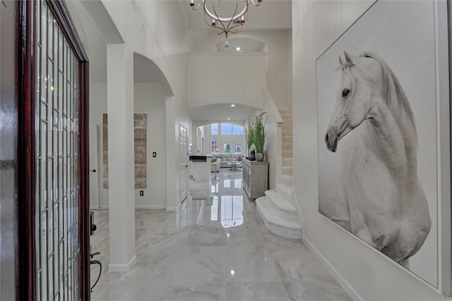entryway with arched walkways, baseboards, a towering ceiling, and marble finish floor