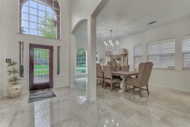 foyer entrance featuring arched walkways, plenty of natural light, a notable chandelier, and visible vents
