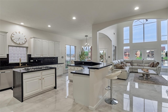 kitchen featuring dark countertops, appliances with stainless steel finishes, arched walkways, recessed lighting, and a kitchen island