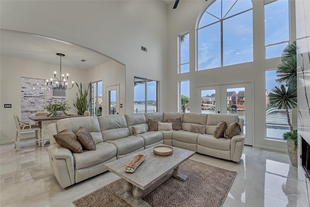 living room with arched walkways, a chandelier, marble finish floor, and a towering ceiling