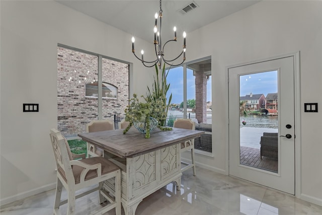 dining room featuring a water view, baseboards, a chandelier, and visible vents