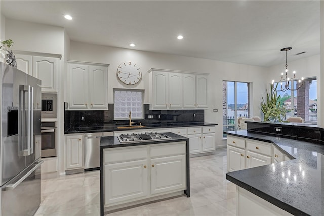 kitchen with stainless steel appliances, a notable chandelier, white cabinetry, and tasteful backsplash