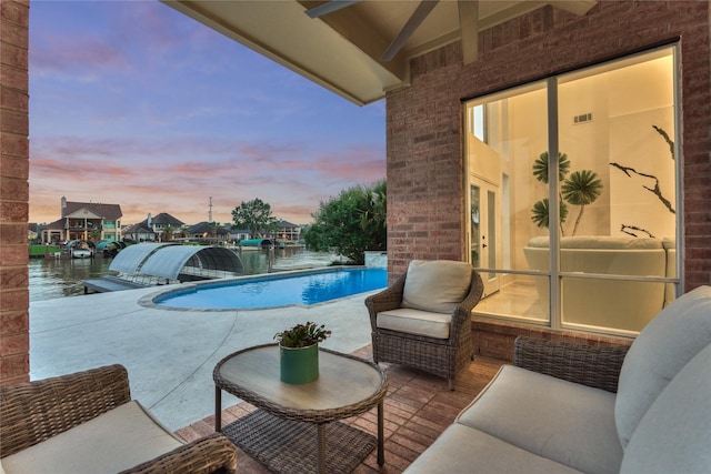 pool at dusk with an outdoor pool, a water view, an outdoor living space, french doors, and a patio