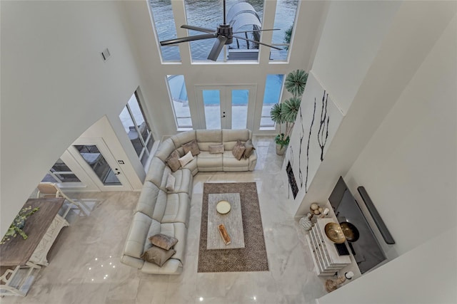 living area featuring marble finish floor, a towering ceiling, and ceiling fan