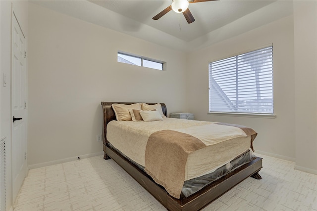 bedroom with ceiling fan, baseboards, and a tray ceiling