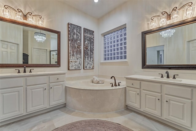 full bath with tile patterned floors, an inviting chandelier, a sink, and a bath