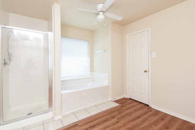 full bathroom featuring wood finished floors, a ceiling fan, a bath, and a stall shower