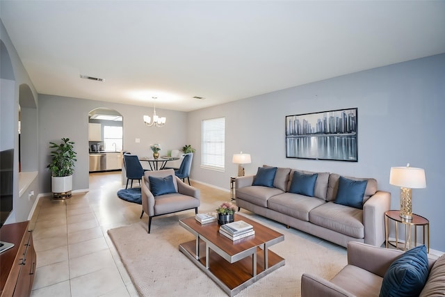 living room with visible vents, arched walkways, light tile patterned floors, baseboards, and a chandelier