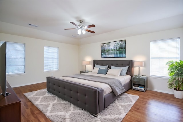 bedroom with baseboards, multiple windows, wood finished floors, and visible vents