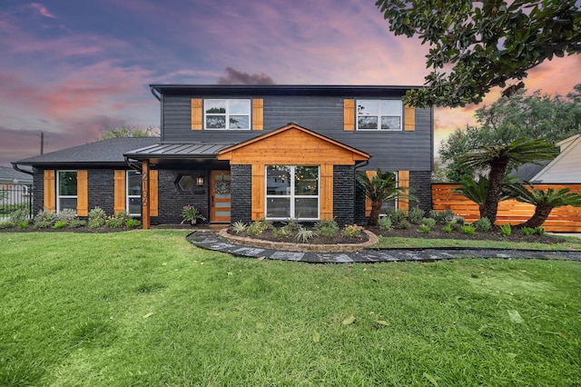 view of front of property with a lawn, a standing seam roof, and fence