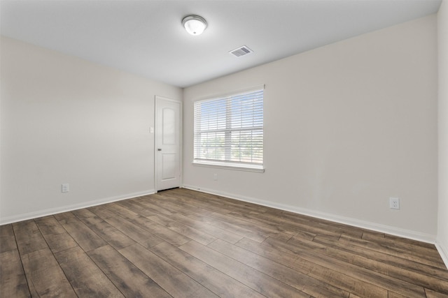 unfurnished room featuring visible vents, baseboards, and dark wood-type flooring
