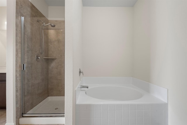 bathroom with a garden tub, a stall shower, and vanity