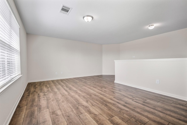 unfurnished room featuring baseboards, visible vents, and wood finished floors