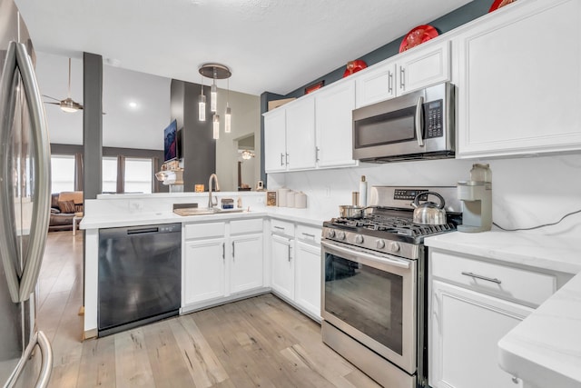 9114 Colony Cove Dr, Spring, TX 77379 - kitchen with a peninsula, light wood-style floors, white cabinetry, a sink, and appliances with stainless steel finishes