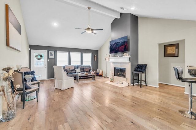9114 Colony Cove Dr, Spring, TX 77379 - living room featuring beamed ceiling, high vaulted ceiling, a tile fireplace, a ceiling fan, and light wood-style flooring
