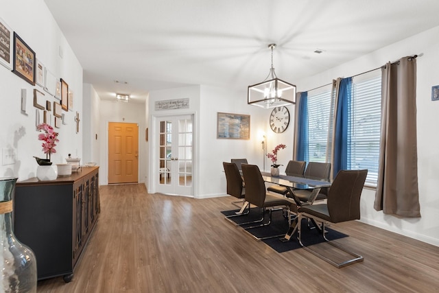 dining area featuring plenty of natural light, wood finished floors, and an inviting chandelier