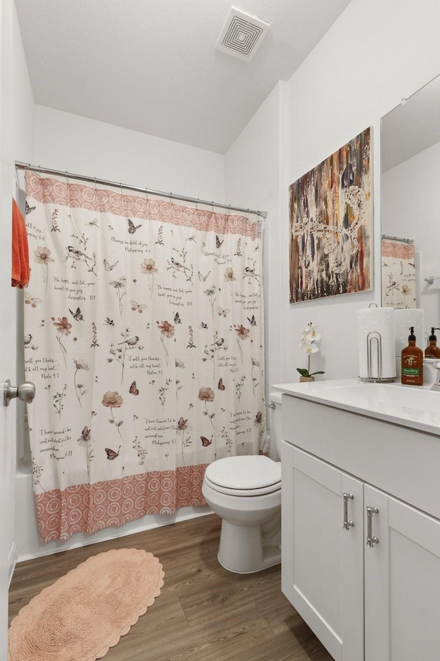 full bathroom with shower / bath combination with curtain, visible vents, wood finished floors, vanity, and toilet