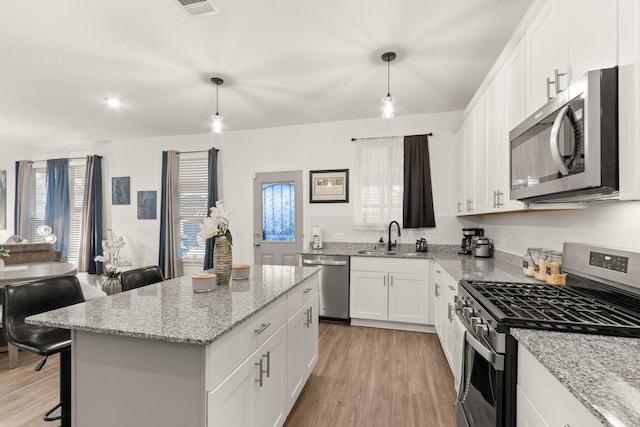 kitchen featuring a healthy amount of sunlight, a center island, light wood-type flooring, a sink, and stainless steel appliances