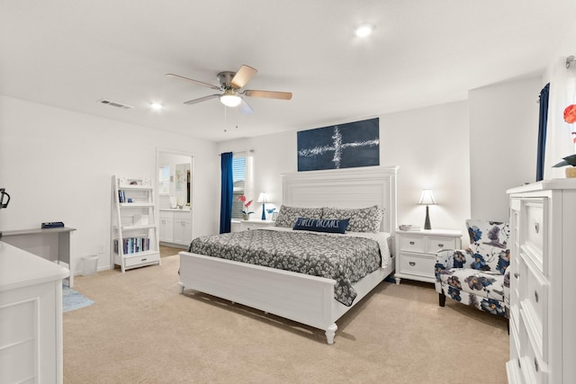 bedroom with visible vents, a ceiling fan, ensuite bath, and light colored carpet