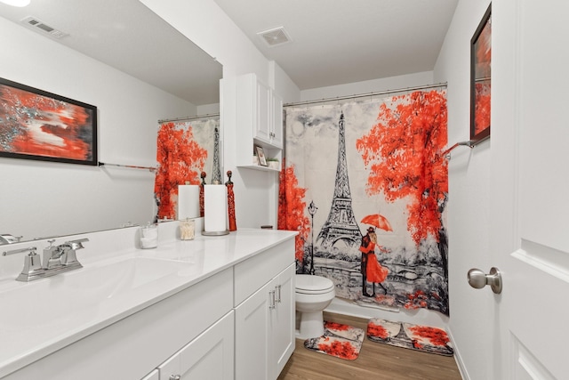 full bath featuring toilet, visible vents, wood finished floors, and vanity