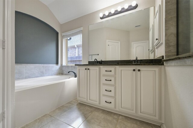 bathroom with double vanity, a garden tub, tile patterned flooring, vaulted ceiling, and a sink
