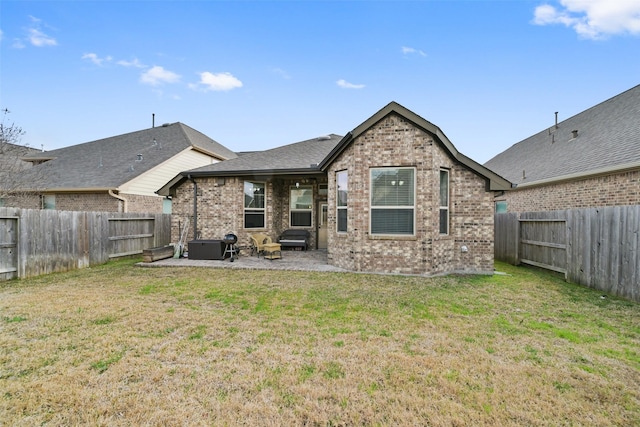 back of property featuring a lawn, brick siding, a fenced backyard, and a patio area