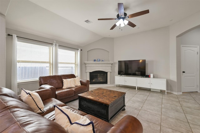 living room featuring visible vents, a glass covered fireplace, a ceiling fan, light tile patterned floors, and vaulted ceiling